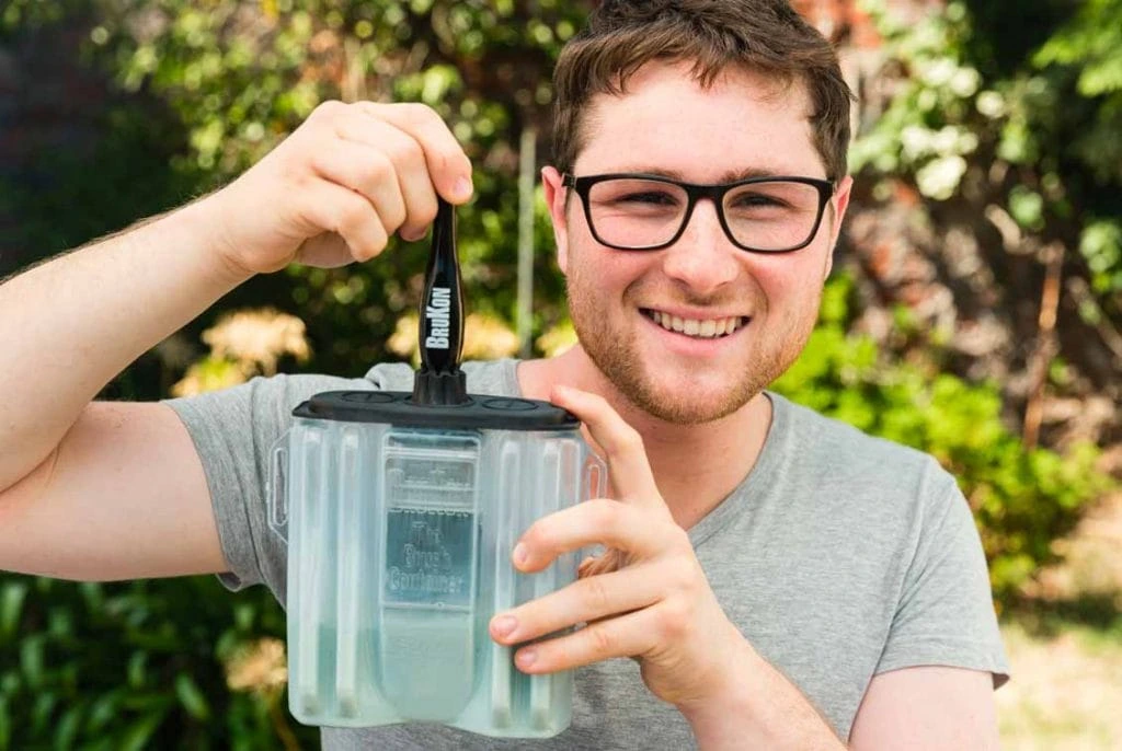 A man holding a BruKon paint brush cleaner with a paint brush inside