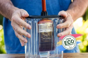 A person holding a clear eco-friendly BruKon paint brush cleaner container with a brush inside